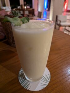 A refreshing piña colada served in a tall glass, topped with a sprig of mint.