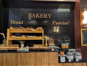 Bakery section in a resort buffet showcasing an array of freshly baked pastries, breads, and desserts displayed on a rustic wooden counter.