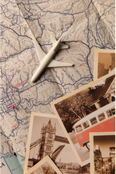A collection of travel photos and a small model airplane placed on an open map, showcasing various travel destinations for travel insurance.