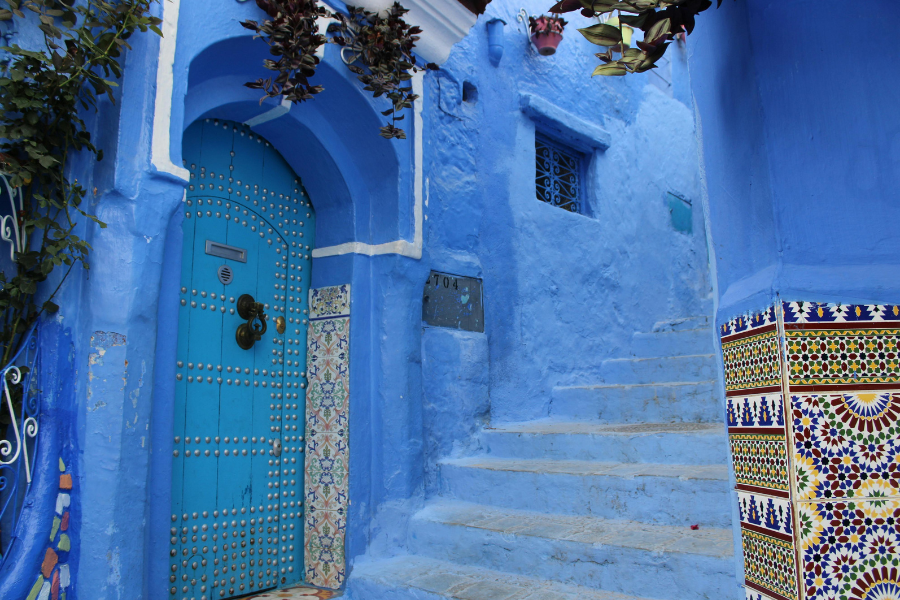 A narrow blue alleyway in Chefchaouen, Morocco, with vibrant blue walls and rustic stone steps.