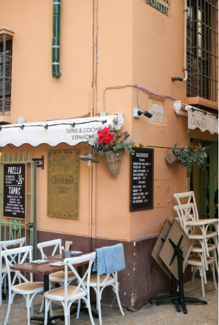 Cozy outdoor seating at a restaurant in Malaga, Spain, with vibrant flowers and rustic decor.