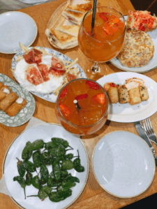 A variety of tapas dishes on a wooden table alongside refreshing drinks.