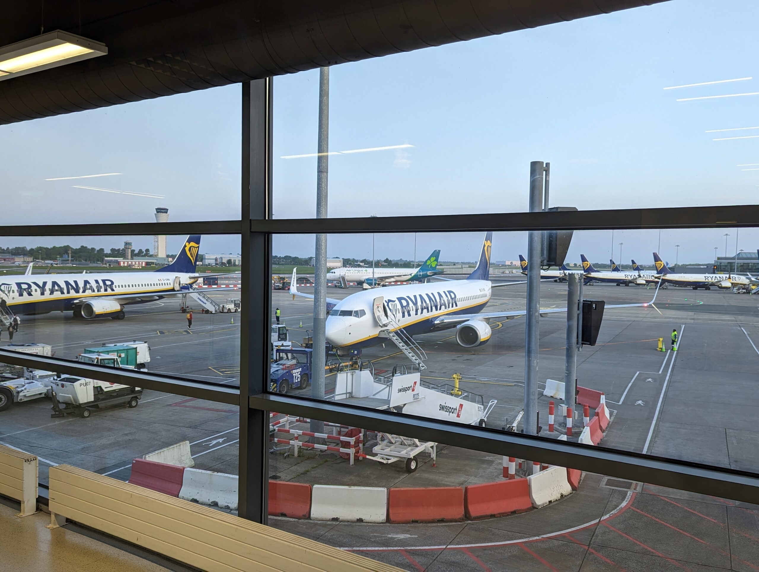 A Ryanair airplane parked at the terminal, viewed through a large window.