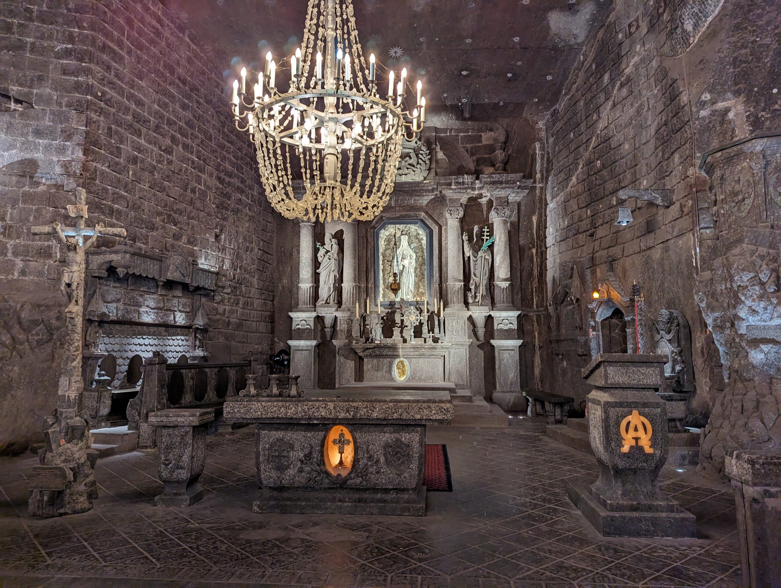 Main chamber of the Wieliczka Salt Mine in Poland with salt chandeliers, carved walls, and a polished stone floor.