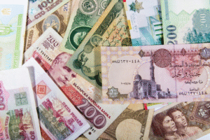 Close-up of various foreign banknotes and coins spread out on a table, showing different currencies and colorful designs.