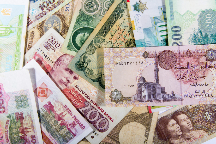 Close-up of various foreign banknotes and coins spread out on a table, showing different currencies and colorful designs.